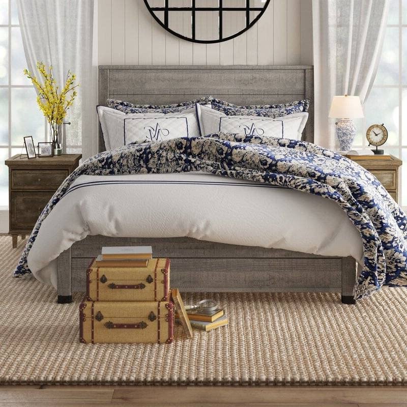 A neatly arranged bedroom with a bed, a dresser, and a suitcase placed beside it.