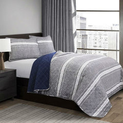 A bed featuring a gray and blue striped comforter, neatly arranged with pillows at the headboard.