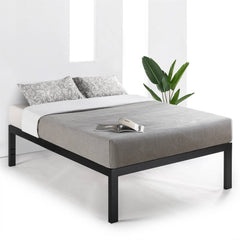 A black-framed bed with a green plant resting on the mattress, creating a cozy and inviting atmosphere.