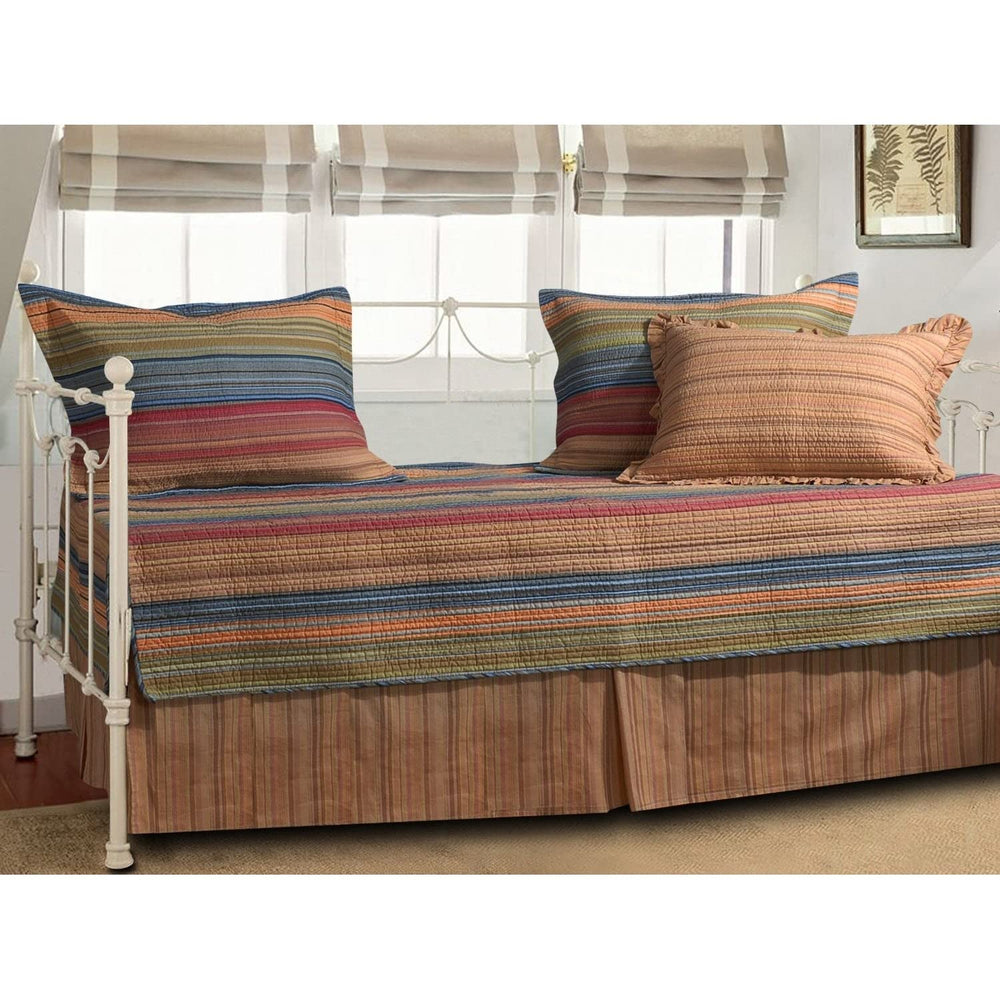 A striped day bed adorned with colorful pillows and a vibrant blanket, creating a cozy and inviting atmosphere.