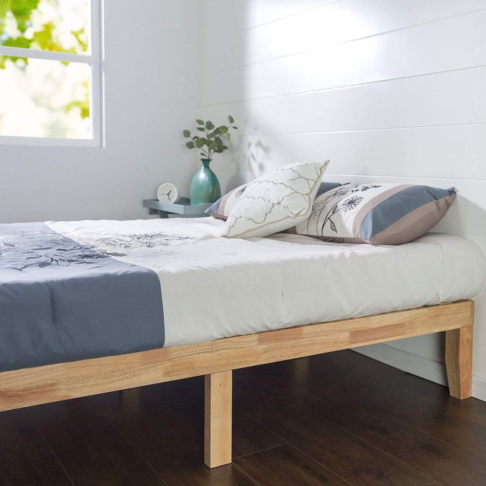 A wooden bed frame set against a white wall, emphasizing a serene and uncluttered bedroom environment.