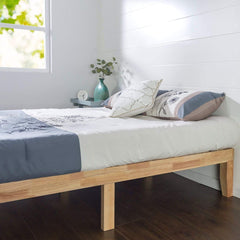 A wooden bed frame set against a white wall, emphasizing a serene and uncluttered bedroom environment.