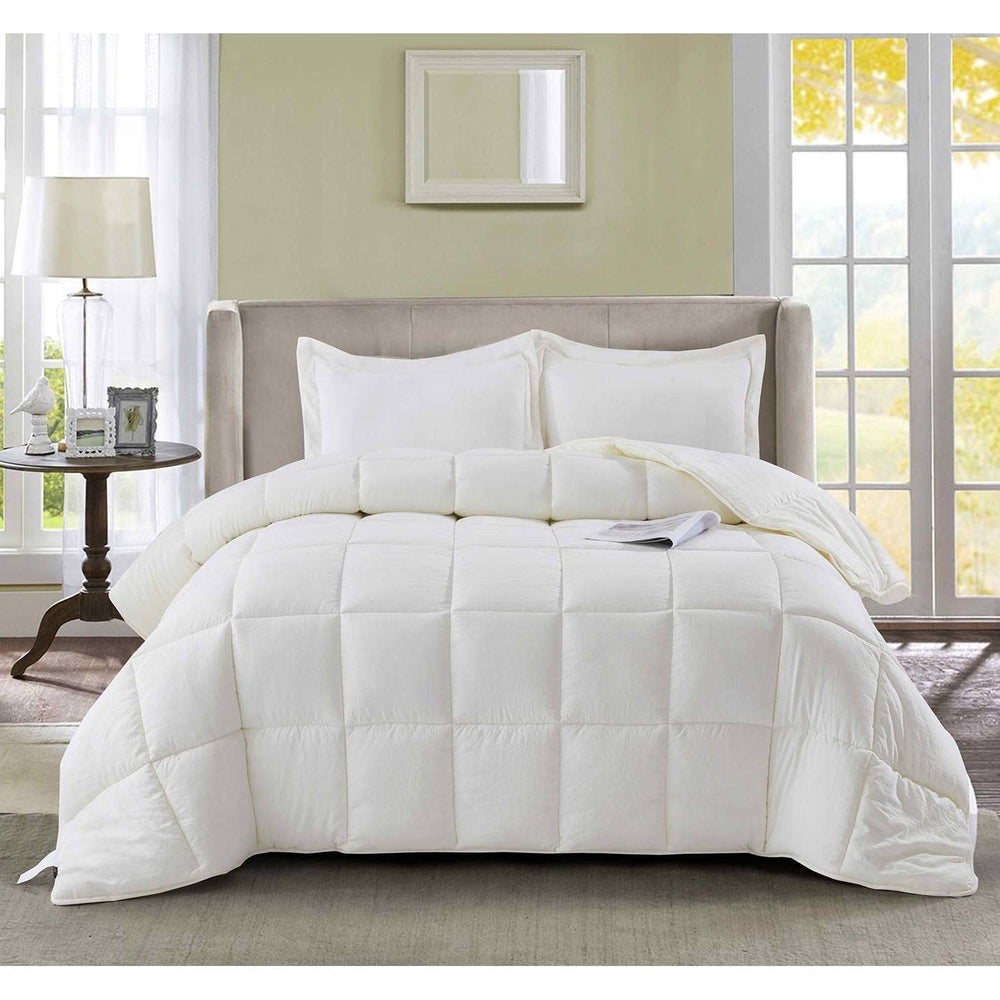 A white comforter and multiple pillows arranged on a bed, offering a soft and comfortable sleeping space.