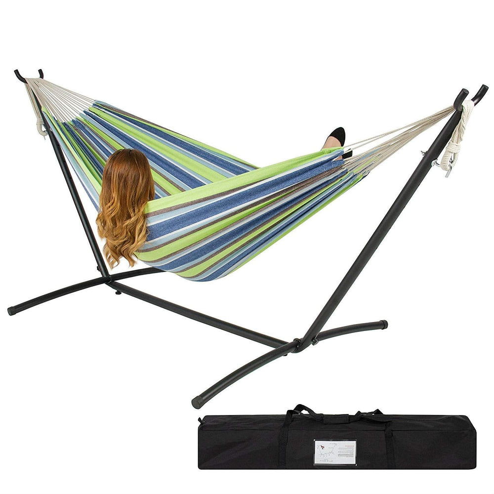 A woman sits comfortably in a hammock with a bag, surrounded by a serene outdoor setting.
