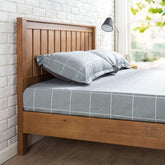 A wooden bed frame adorned with a blue and white checkered bedspread, creating a cozy and inviting atmosphere.