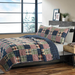A stylish bed with a plaid quilt and an assortment of pillows for added comfort.