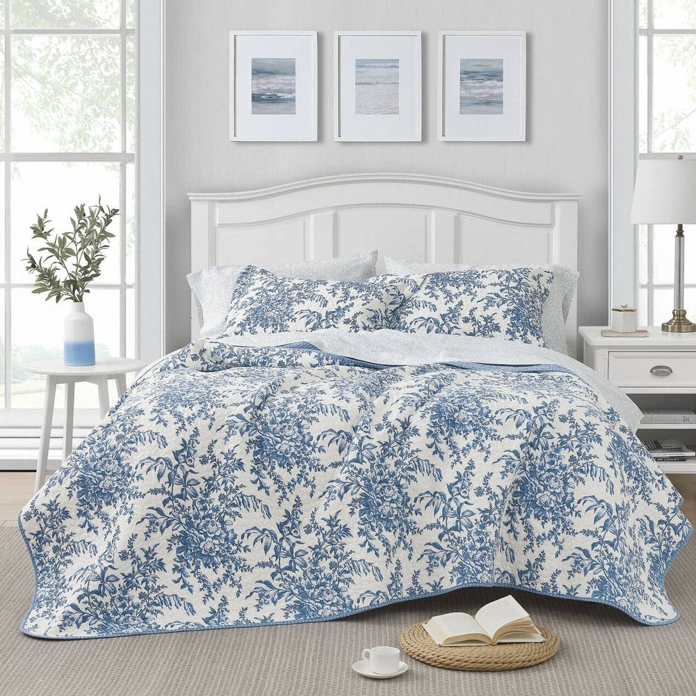 The floral bedspread in blue and white adds a charming touch to the bedroom, creating a cozy atmosphere.