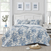 The floral bedspread in blue and white adds a charming touch to the bedroom, creating a cozy atmosphere.