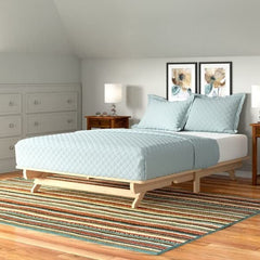 A bed featuring a wooden frame adorned with a blue bedspread.