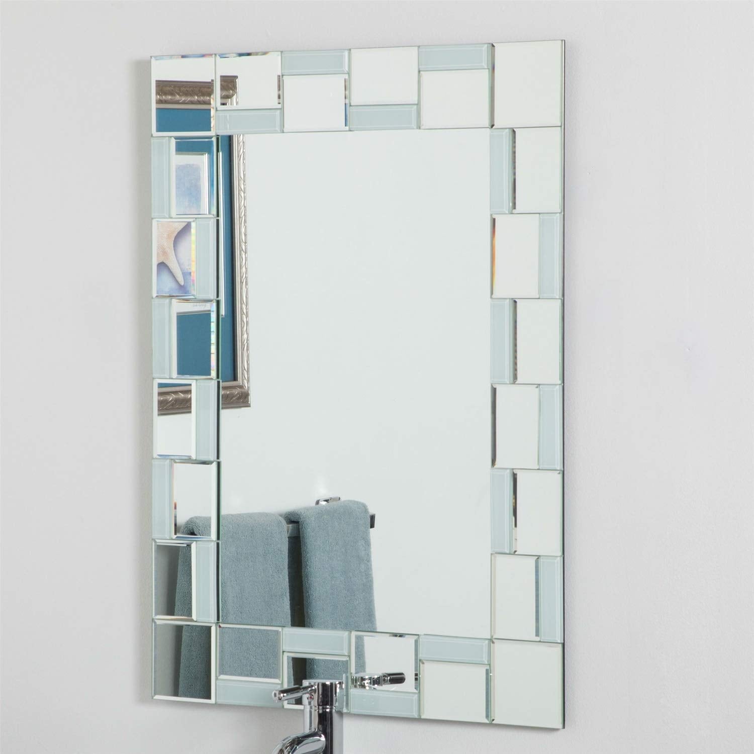 A bathroom mirror framed by square glass tiles, reflecting the surrounding space.