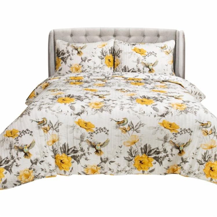 A bed featuring a yellow and gray floral comforter and a white pillow, creating a bright and inviting look.