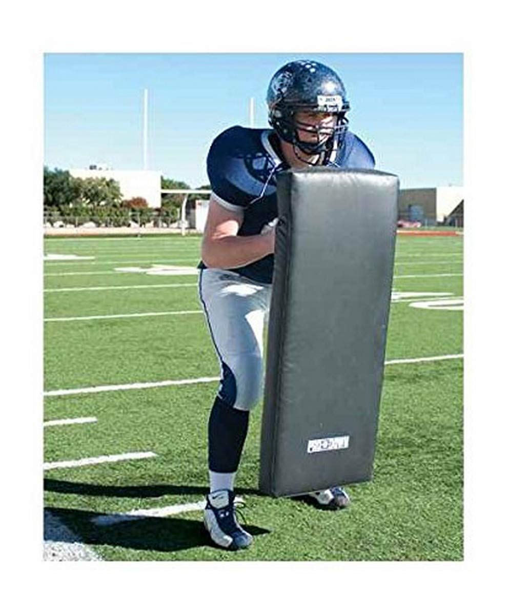 A football player grips a large pad on the field, preparing for a training session or a game.