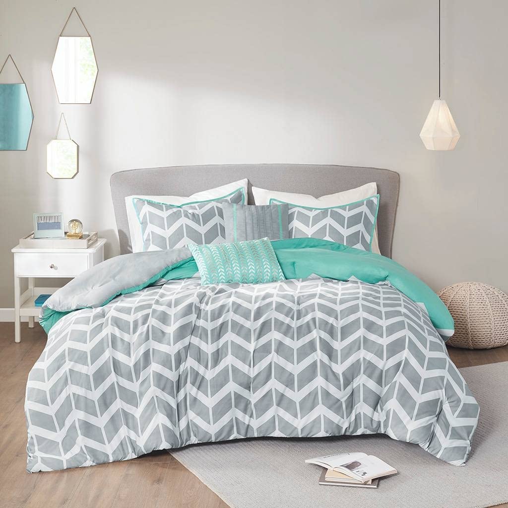 A gray and turquoise comforter set draped over a white bed, creating a stylish and inviting bedroom atmosphere.