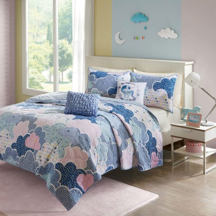 A blue and pink comforter featuring a cloud pattern, adding a whimsical touch to a bedroom decor.