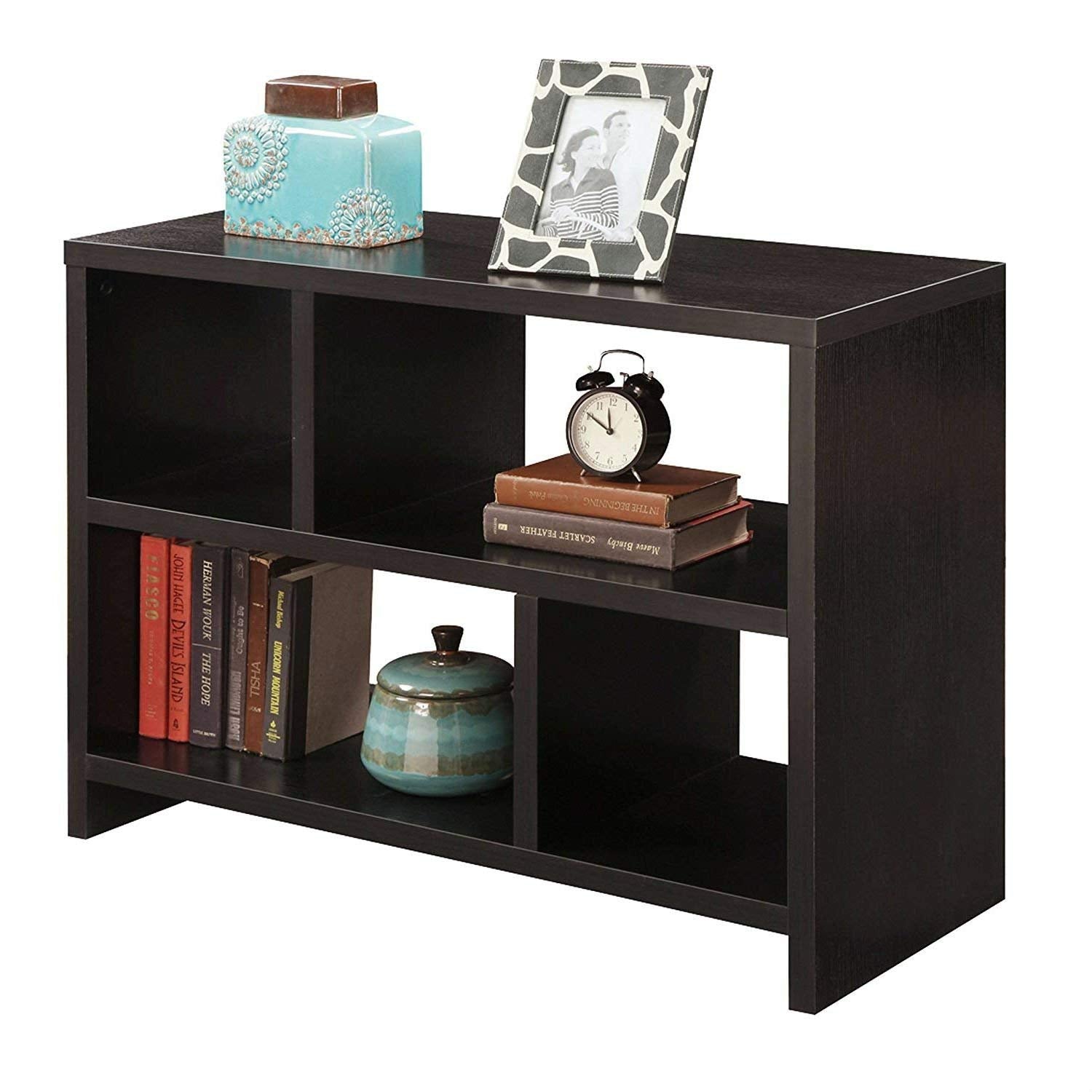 A black bookshelf filled with books and topped with a clock, adding a functional touch to the decor.