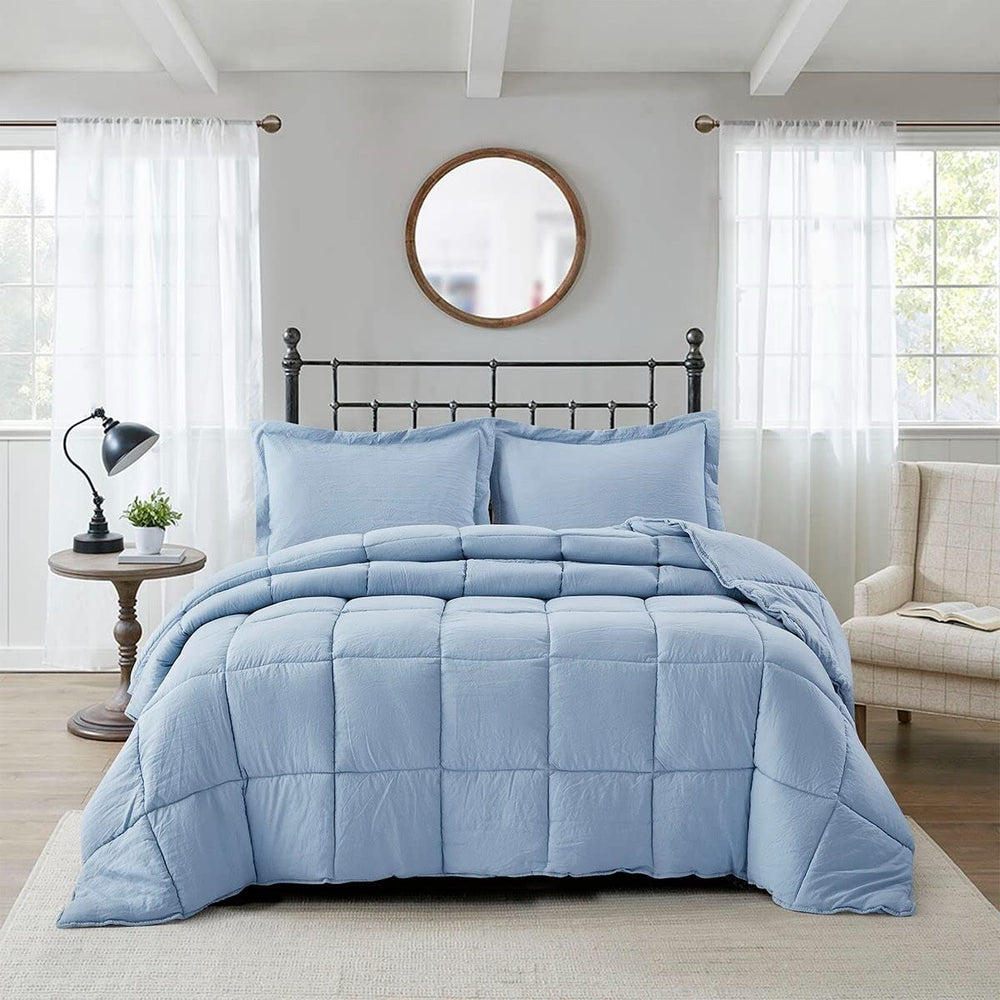 A blue comforter draped over a black frame, with decorative pillows placed at the head of the bed.