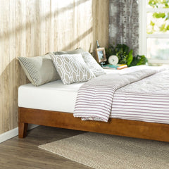 A bed with a sturdy wooden frame, adorned with a colorful striped pillow, enhancing the room's comfort.