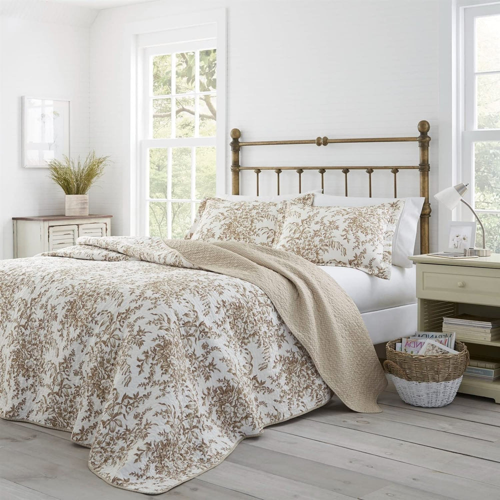  A white bed adorned with a tan comforter, accompanied by a white nightstand, creates a serene bedroom atmosphere.