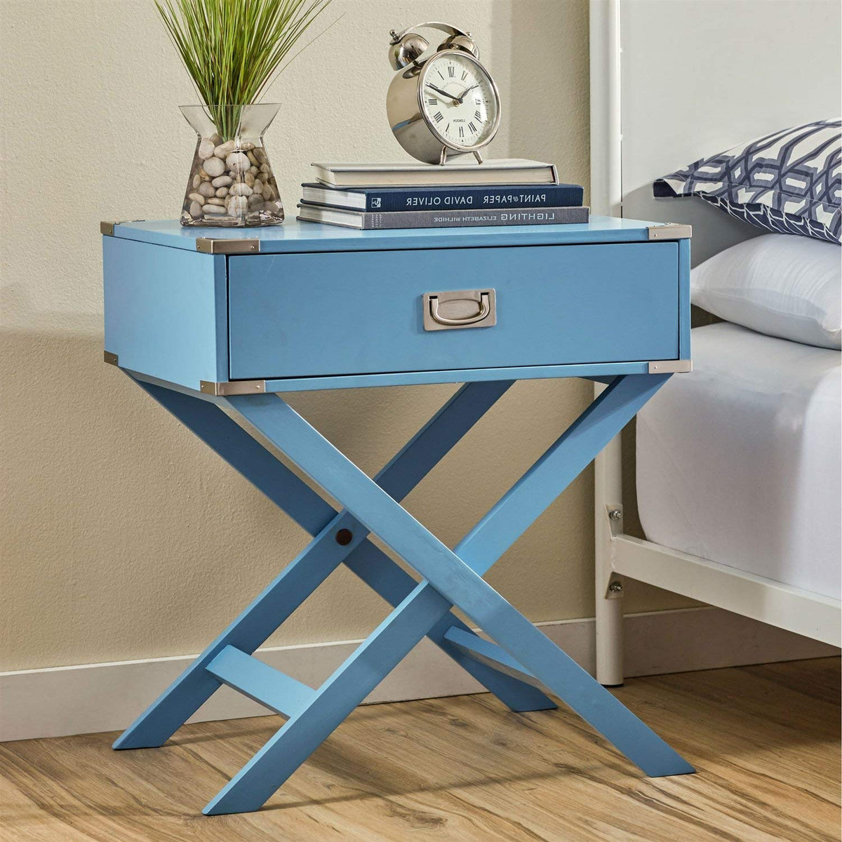 A blue nightstand with a clock and an open book resting on it, creating a cozy bedside scene.
