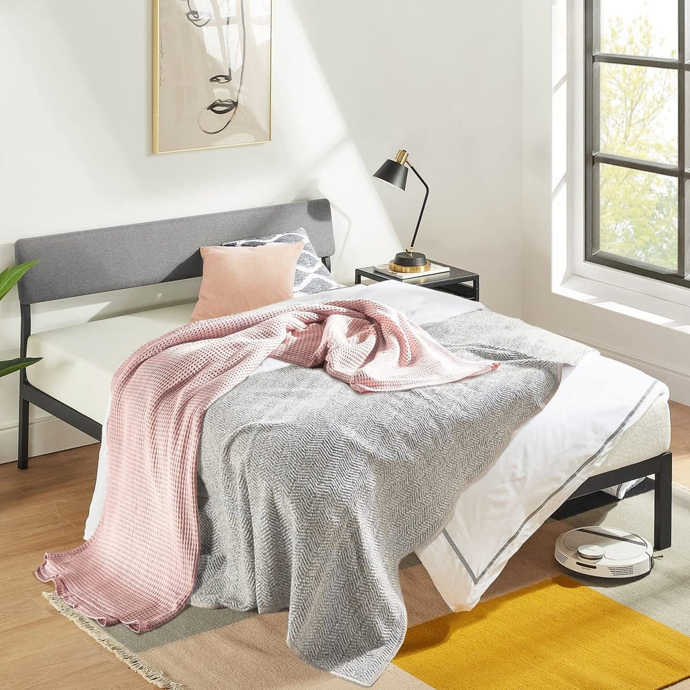 A bed dressed with a pink blanket and a sunny yellow pillow, creating a warm atmosphere.