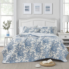 The floral bedspread in blue and white adds a charming touch to the bedroom, creating a cozy atmosphere.