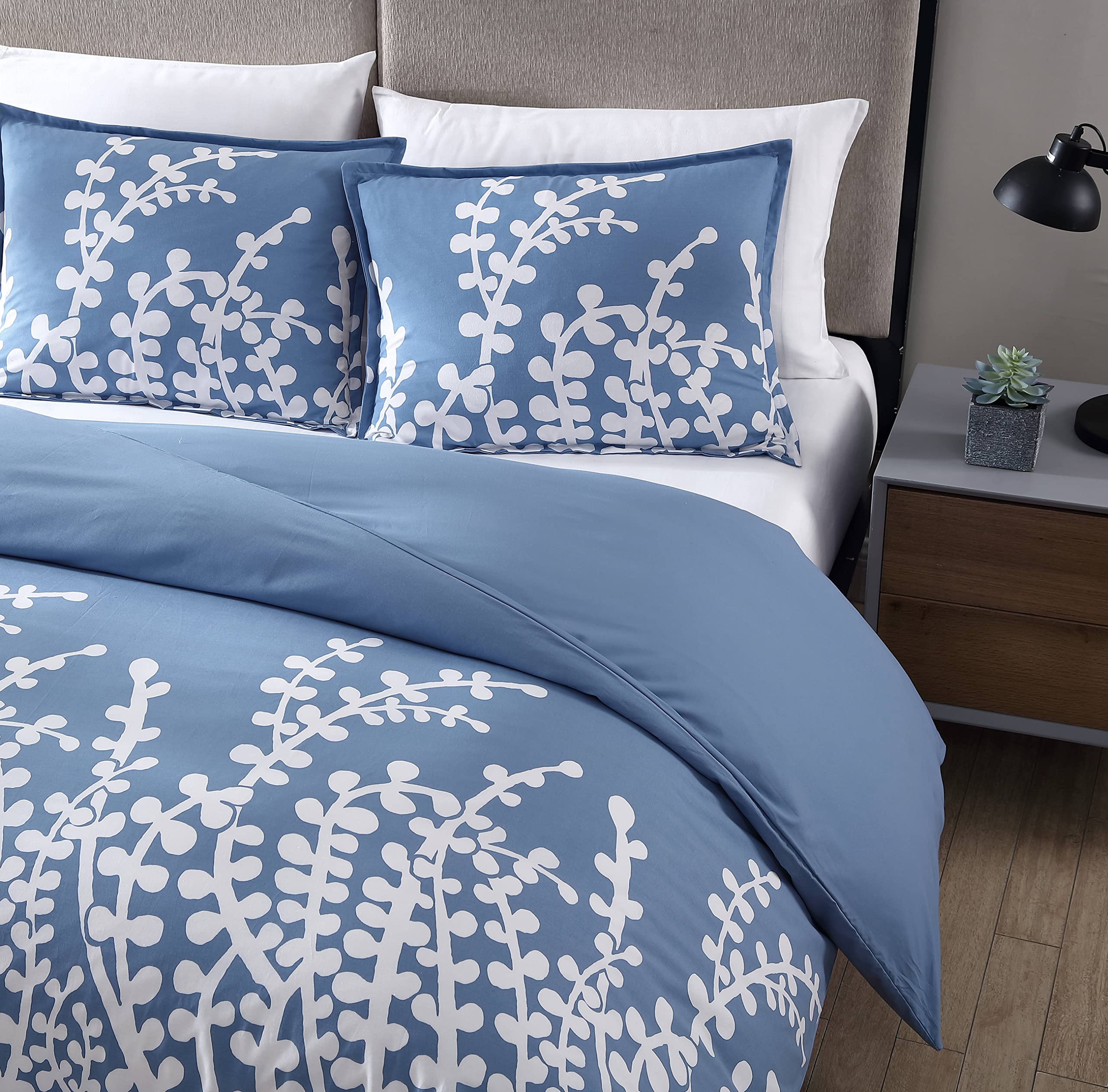 A blue comforter featuring delicate white flowers, adding a touch of elegance to the bedding.
